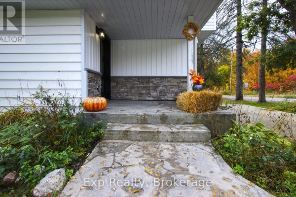 Front entrance porch with concrete steps, stone siding, and fall decorations including a pumpkin and hay bale. - 2988 County 44 Road, Havelock Belmont Methuen
