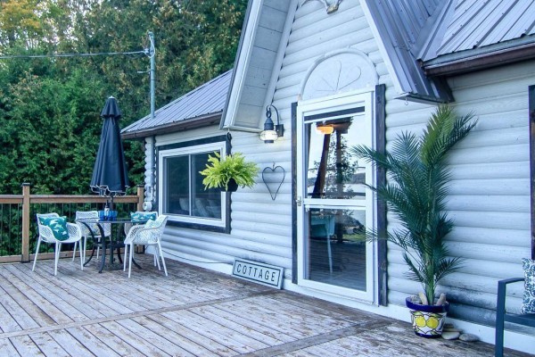 Deck seating area with table and chairs next to the cottage entrance. - 299 Mallory Beach Road, South Bruce Peninsula