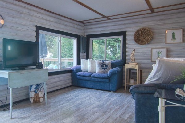 Living room with two blue sofas, a television, and large windows. - 299 Mallory Beach Road, South Bruce Peninsula