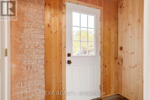 Interior view of an entrance with a white door, brick wall, and wood-paneled walls. - 2993 Gulfstream Way, Mississauga