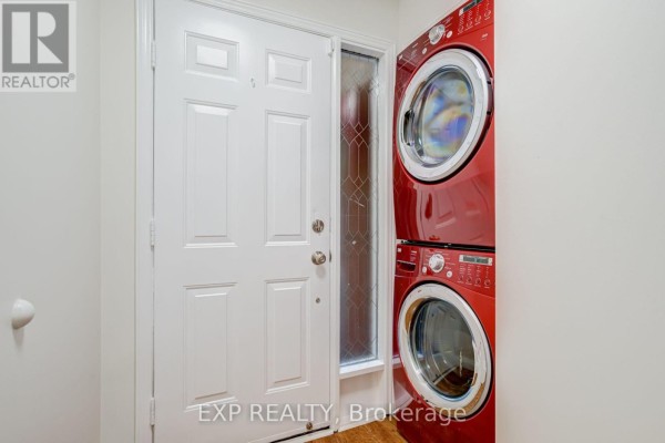 White front door with a side window next to a red stacked washer and dryer. - 2993 Gulfstream Way, Mississauga