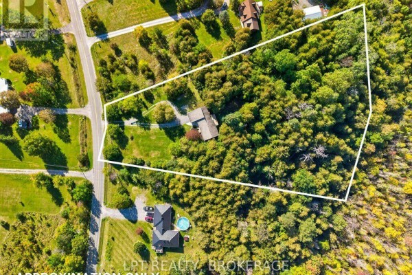 Aerial view of a property showing a house surrounded by trees and a white outline of the property boundary. - 2994 Campbell Road, Frontenac