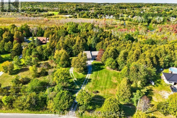 Aerial view of a house with a long driveway surrounded by mature trees and distant fields. - 2994 Campbell Road, Frontenac