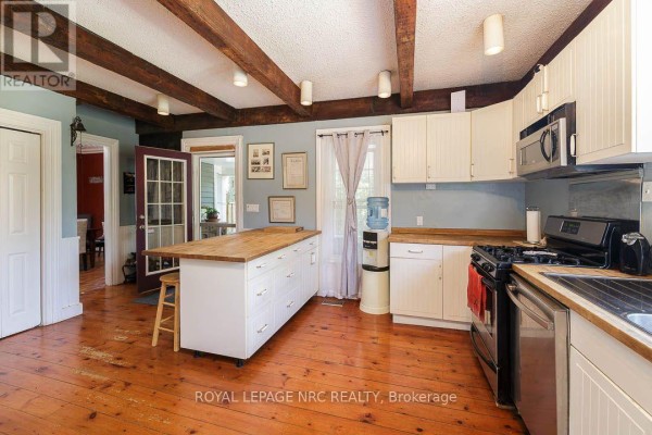 Covered front porch with wicker seating, patterned rug, and white railing. - 2996 Ninth Street, Lincoln