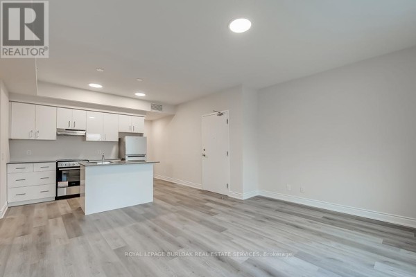 Living and dining area with light wood laminate flooring and white walls. - 2a - 259 King Street E, Hamilton