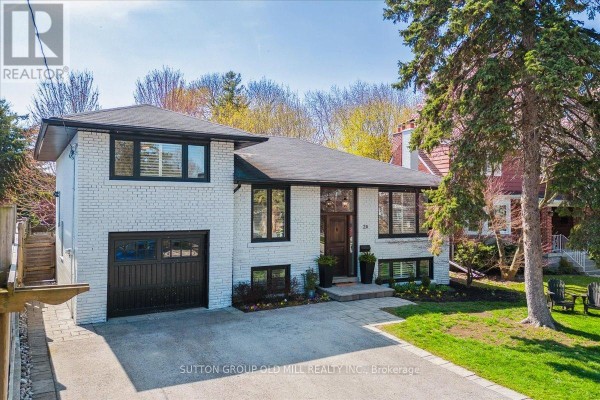 Slightly angled front exterior view of a white brick house with a sloped driveway and mature trees. - 2a Elton Crescent, Toronto