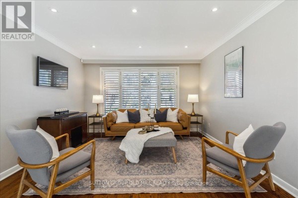 Living room with a tan leather sofa, two grey armchairs, a fireplace, and plantation shutters. - 2a Elton Crescent, Toronto