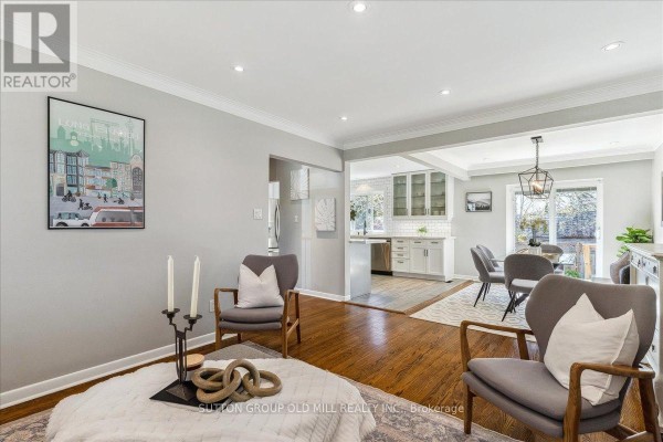 Living room with grey armchairs and view into the open concept kitchen and dining area. - 2a Elton Crescent, Toronto