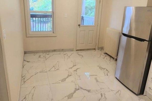 Small dining area with large window, door, and stainless steel refrigerator. - 2b-3rd Floor - 1030 St Clair Avenue, Toronto