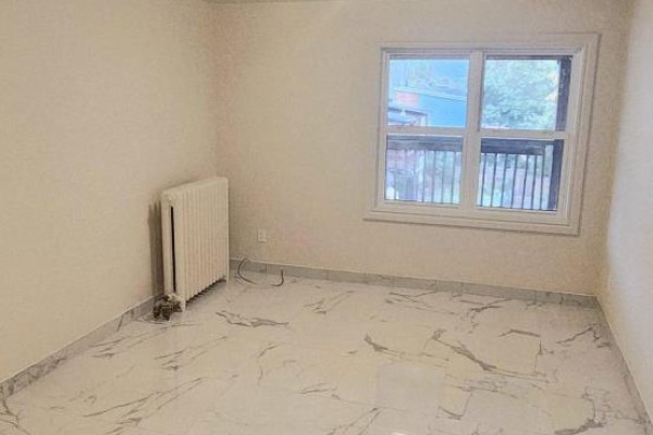 Empty room with white walls, radiator, and window overlooking greenery. - 2b-3rd Floor - 1030 St Clair Avenue, Toronto