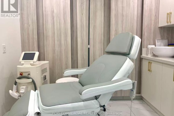 A medical-style treatment chair and laser machine in a room with wood-paneled walls. - 2n - 26 Bellair Street, Toronto
