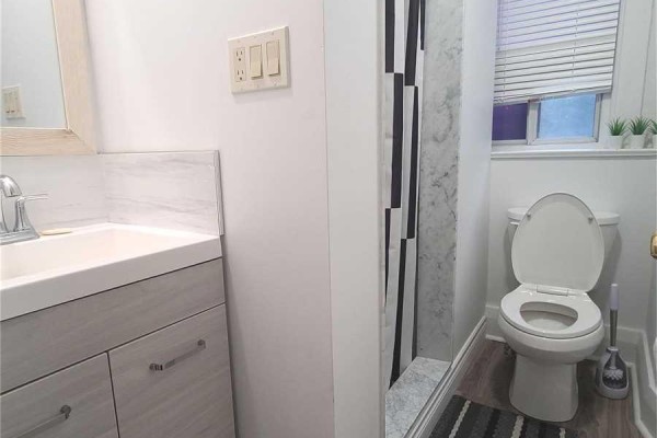Small bathroom with a vanity, sink, toilet, and shower with black and white striped curtains. - 2nd Fl - 1353 St Clair Avenue W, Toronto