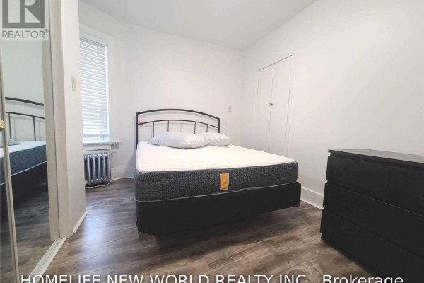 Bedroom with a double bed, black metal frame, mattress, white pillows, and a black dresser against a white wall. - 2nd Fl - 1353 St Clair Avenue W, Toronto