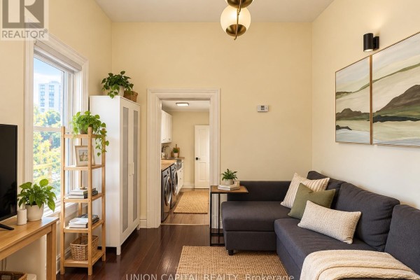 Living area with a sectional sofa, end table, and a view into the laundry room. - 2nd Fl - 459 Queen Street W, Toronto