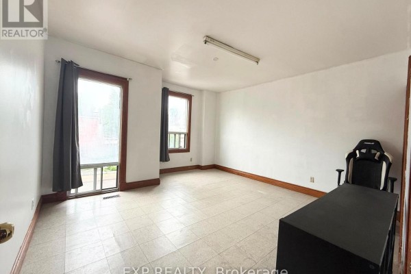 Room with two windows, tiled floor, and a black desk with an office chair. - 2nd Fl - 759 Gerrard Street E, Toronto