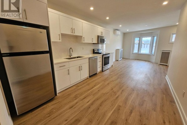 Bright kitchen with white cabinetry, a large island, and stainless steel appliances. - 2nd Floor - 3293 Dundas Street W, Toronto