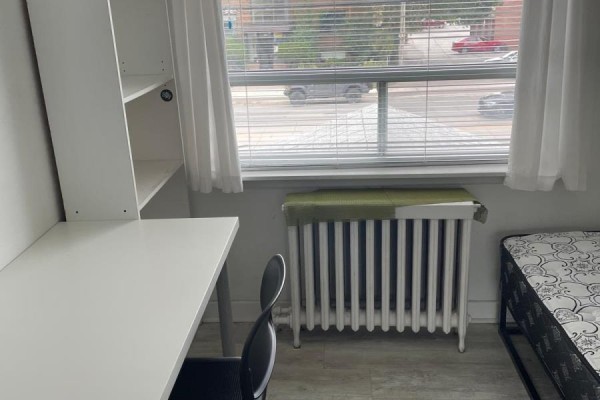 White desk and chair next to a radiator and window with blinds overlooking the street. - 2nd Floor Room - 2518 Lake Shore Boulevard, Toronto