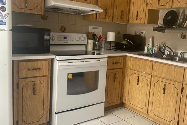 Kitchen with light wood cabinets, white appliances including a stove and microwave, and tiled floor. - 2nd Floor Room - 2518 Lake Shore Boulevard, Toronto