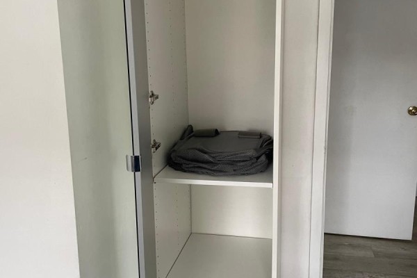 Open white closet with a shelf holding a folded grey item against a white wall. - 2nd Floor Room - 2518 Lake Shore Boulevard, Toronto