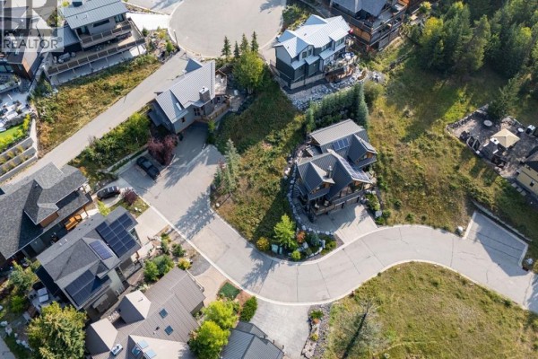 Aerial view of a curved street lined with houses on a heavily wooded incline. - 3, 126 Benchlands Terrace, Canmore