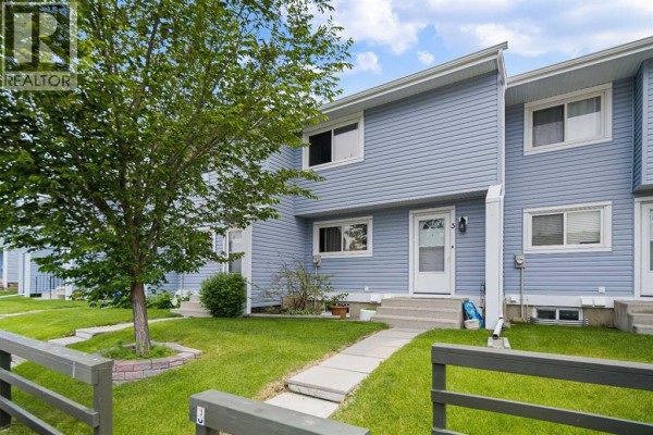 Wooden deck with chairs, table, and barbecue on the side of the townhouse. - 3, 195 Manora Place Ne, Calgary
