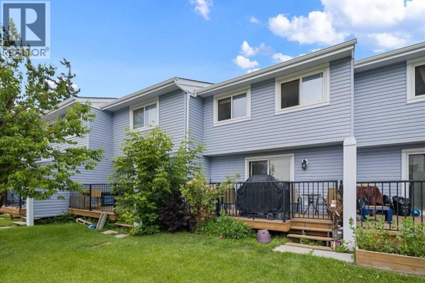 Rear exterior of the blue townhouse complex showing balconies and green lawn. - 3, 195 Manora Place Ne, Calgary