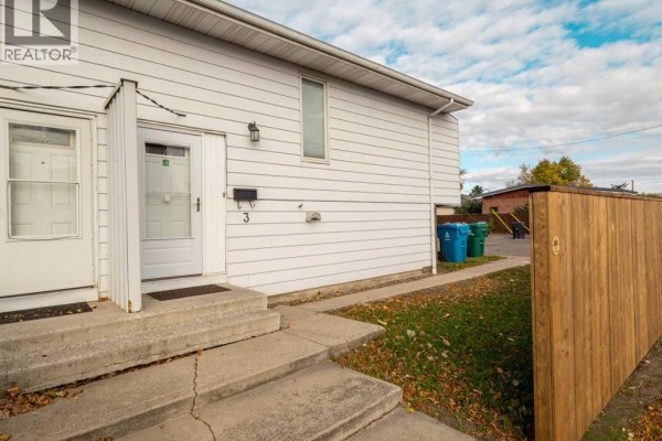 Front entrance of townhouse with concrete stairs and white doors. Wooden fence along the side. - 3, 2145 5 Avenue N, Lethbridge
