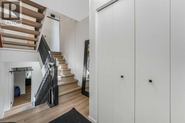 Interior view of a staircase with natural wood treads, black spindles, and white walls. - 3, 7900 Silver Springs Road Nw, Calgary