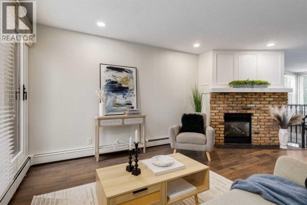 Living room with a brick fireplace, armchair, console table, and large abstract wall art. - 3, 906 4 Avenue Nw, Calgary