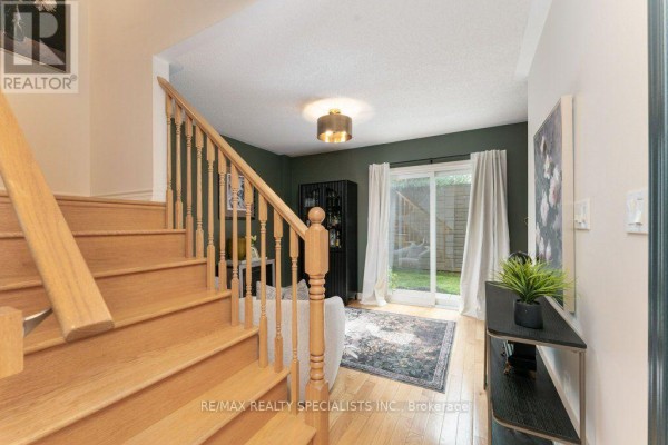 Living area with light wood floors, wooden staircase, sliding glass door to backyard, and dark green walls. - 3 - 1115 Haig Boulevard, Mississauga