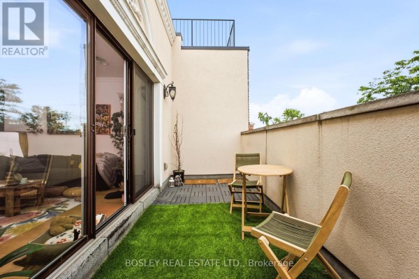Balcony with artificial grass, table, chairs, and view of building exterior. - 3 - 115 Roncesvalles Avenue, Toronto