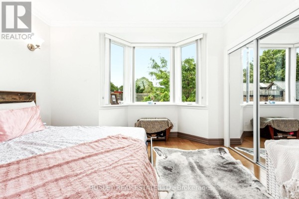 Bedroom with bay window, bed, and mirrored closet doors. - 3 - 115 Roncesvalles Avenue, Toronto