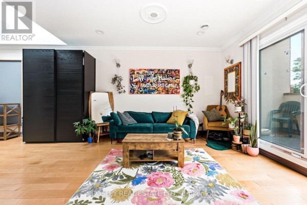 Living room with sofa, coffee table, colorful rug, and large black closet doors. - 3 - 115 Roncesvalles Avenue, Toronto