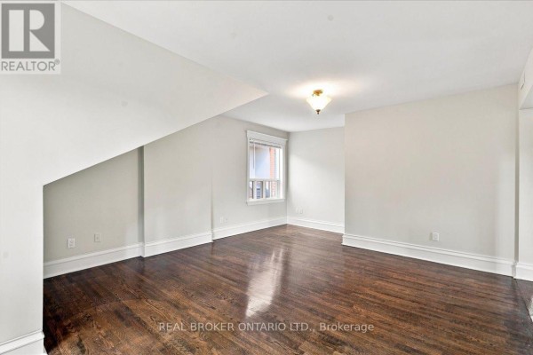 Attic bedroom with slanted ceiling, dark hardwood floor, and window. - 3 - 12 Foxbar Road, Toronto