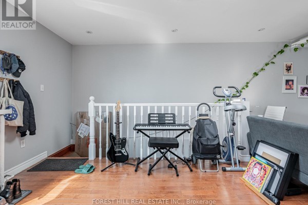 A room with light gray walls, hardwood floors, a white railing, keyboard, and exercise equipment. - 3 - 12 Salem Avenue, Toronto