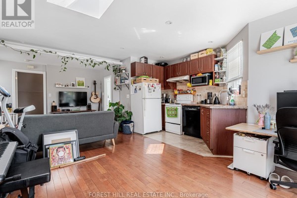 Open concept living area with hardwood floors, a gray sofa, kitchen cabinets, and appliances. - 3 - 12 Salem Avenue, Toronto