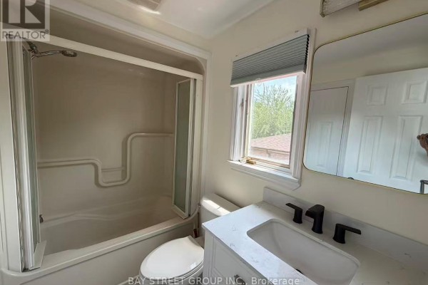 Bathroom with a bathtub/shower combo, toilet, and a vanity with a sink and black faucet. - 3 - 19 Dunsfold Drive, Toronto