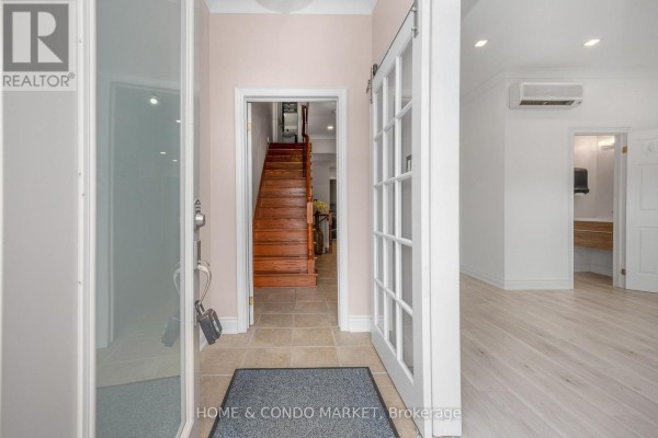 Wooden staircase with metal spindles next to a wet bar with a wine fridge. - 3 - 194 Lakeshore Road W, Mississauga