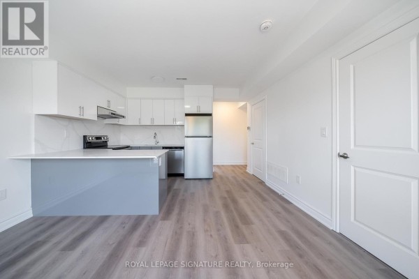 Kitchen with white and grey cabinets, a stainless steel refrigerator, and access to a hallway. - 3 - 2052 Pharmacy Avenue, Toronto
