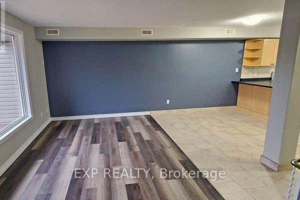 Living area with wood plank flooring, tiled section, and a dark blue accent wall. - 246 Lakeshore Road, St  Catharines