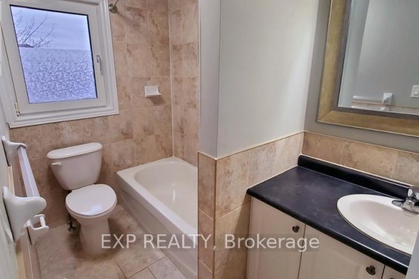 Bathroom with a toilet, bathtub, and vanity with a mirror and tiled walls. - 246 Lakeshore Road, St  Catharines