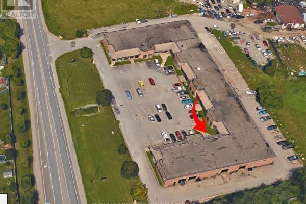Aerial view of a commercial complex with multiple units and a large parking lot. - 3 - 24707 Woodbine Avenue, Georgina