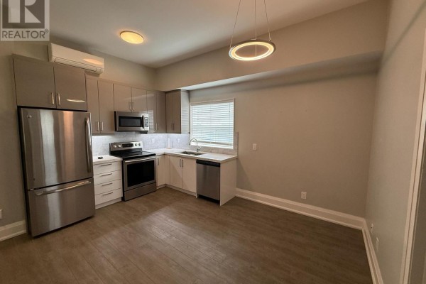 View of a modern kitchen with stainless steel appliances and two-tone cabinets. - 3 - 2548 Eglinton Avenue W, Toronto