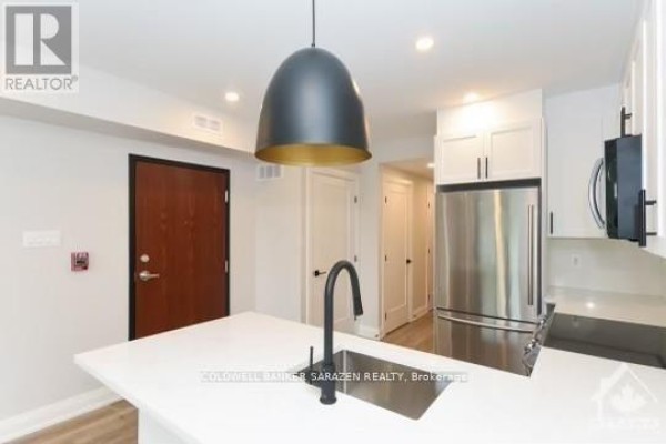Kitchen with white cabinets, stainless steel appliances, and a view down a hallway. - 3 - 27 Monk Street, Ottawa
