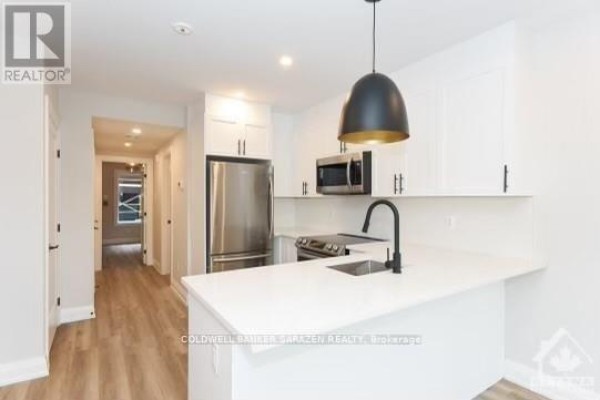 Kitchen with white cabinets, stainless steel refrigerator, microwave, and stove. - 3 - 27 Monk Street, Ottawa