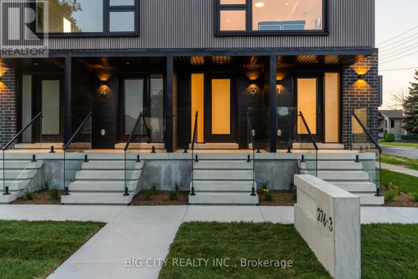 Close-up of townhouse entrances with glass railings, concrete steps, and exterior lighting. - 3 - 276 Lanor Avenue, Toronto