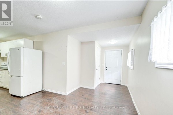 View of kitchenette and open living space with beige walls and dark laminate flooring. - 3 - 303 Moffat Street, Orillia