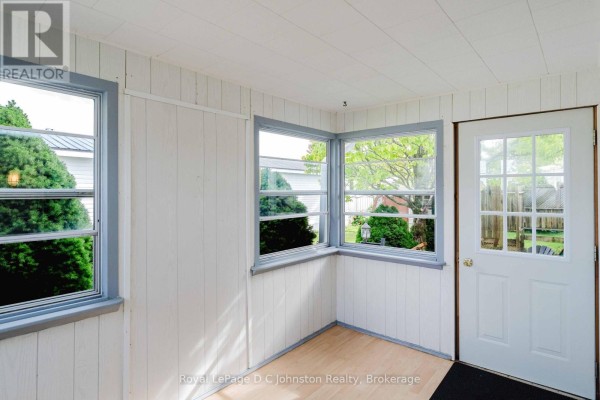 Interior sunroom with white paneled walls, wood-look flooring, and a glass-paned exterior door. - 3 - 332 Concession 6, Saugeen Shores