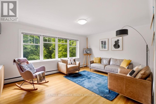 Living room with light hardwood floors, white walls, and a large window. - 3 - 34 Lavergne Street, Ottawa