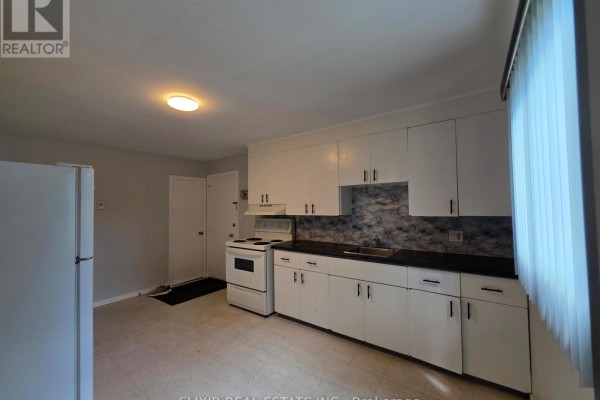 Kitchen with white cabinets, white stove, black countertop, and textured wallpaper. - 3 - 362 Grey Street, Brantford